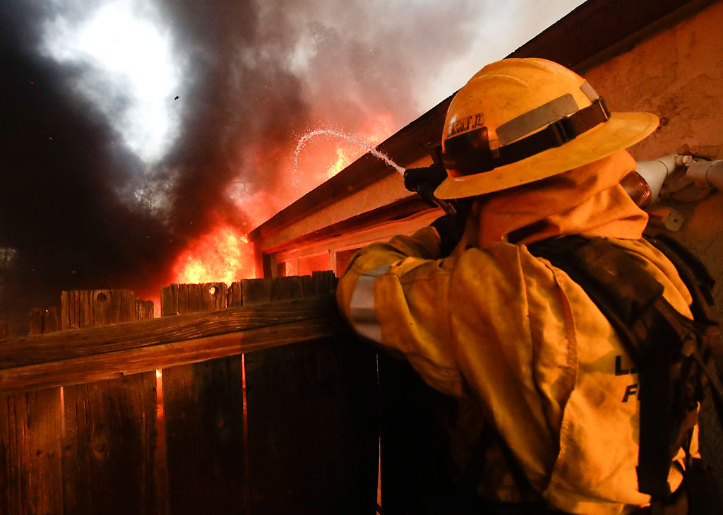 Firefighter puts water on burning house